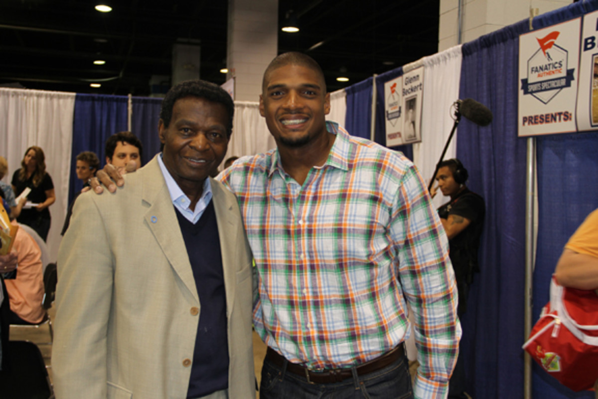 Michael Sam made his first appearance at a sports collectible show, signing at the Fanatics Authentic show in Rosemont, Ill. Among those who reached out to Sam at the event was Lou Brock, left.