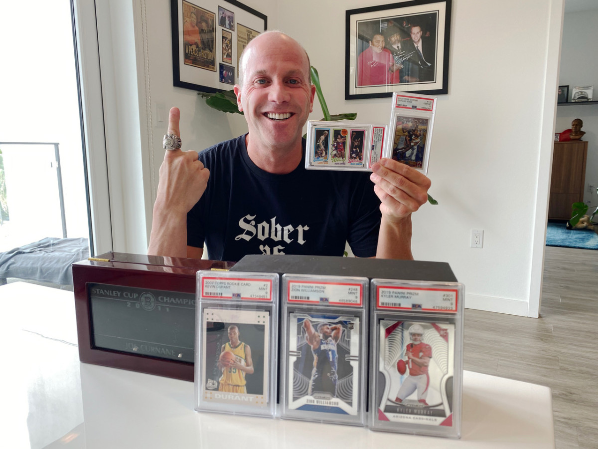 Darren Prince shows off the 2011 Boston Bruins’ Stanley Cup championship ring he purchased, along with some of his top cards.