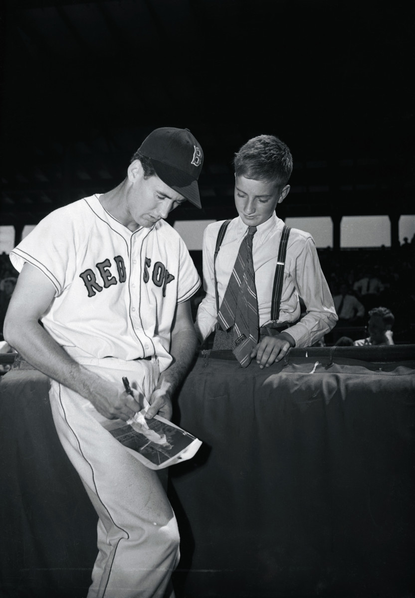 Ted Williams holds a baseball he autographed, while his son John