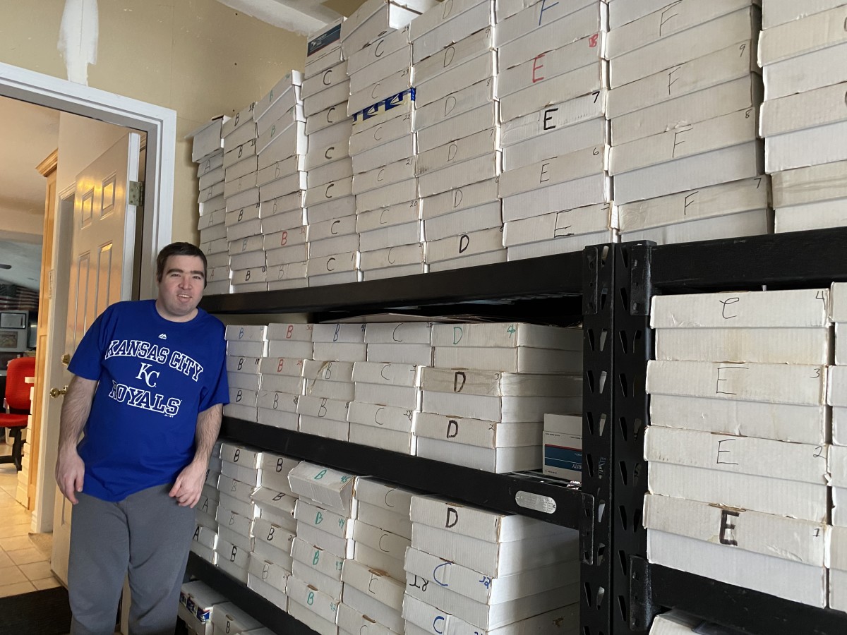 Paul Jones standing by boxes full of baseball cards categorized alphabetically by last name.