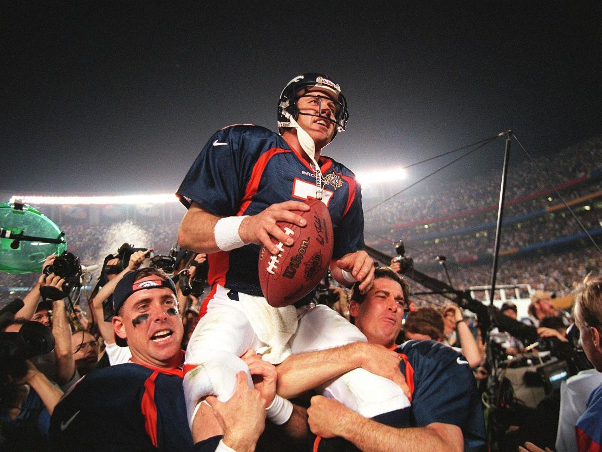 Denver Broncos quarterback John Elway is carried by teammates Ed McCaffrey (L) and Bubby Brister (R) after the Broncos defeated the Green Bay Packers 31-24 to win Super Bowl XXXII in San Diego.