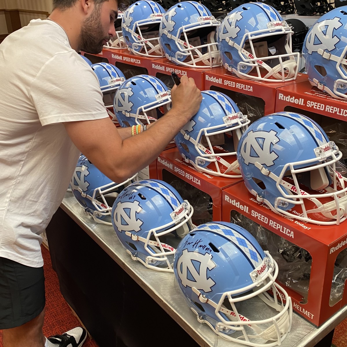 North Carolina quarterback Sam Howell signs helmets for Signature Sports Marketing.
