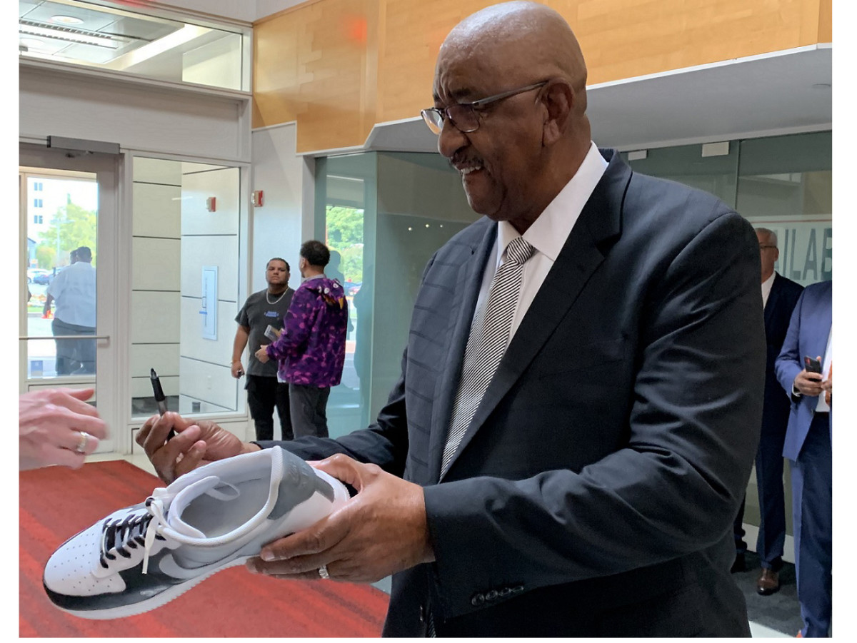 NBA great George Gervin signs a San Antonio Spurs sneaker at the 2022 Basketball Hall of Fame ceremonies.