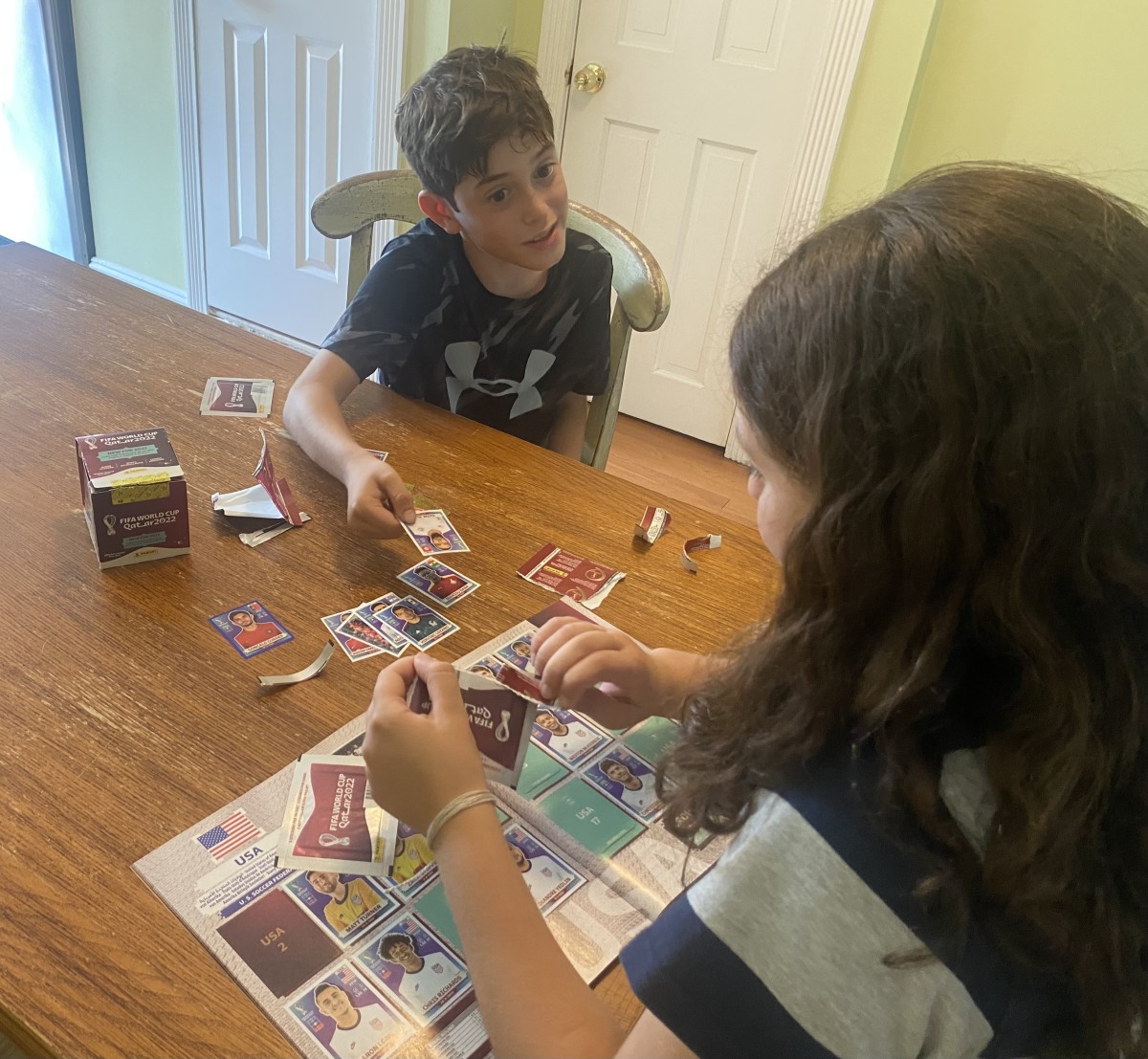 Mark, 10, and Grace Lisi, 13, trade cards from the new 2022 World Cup Sticker Album.
