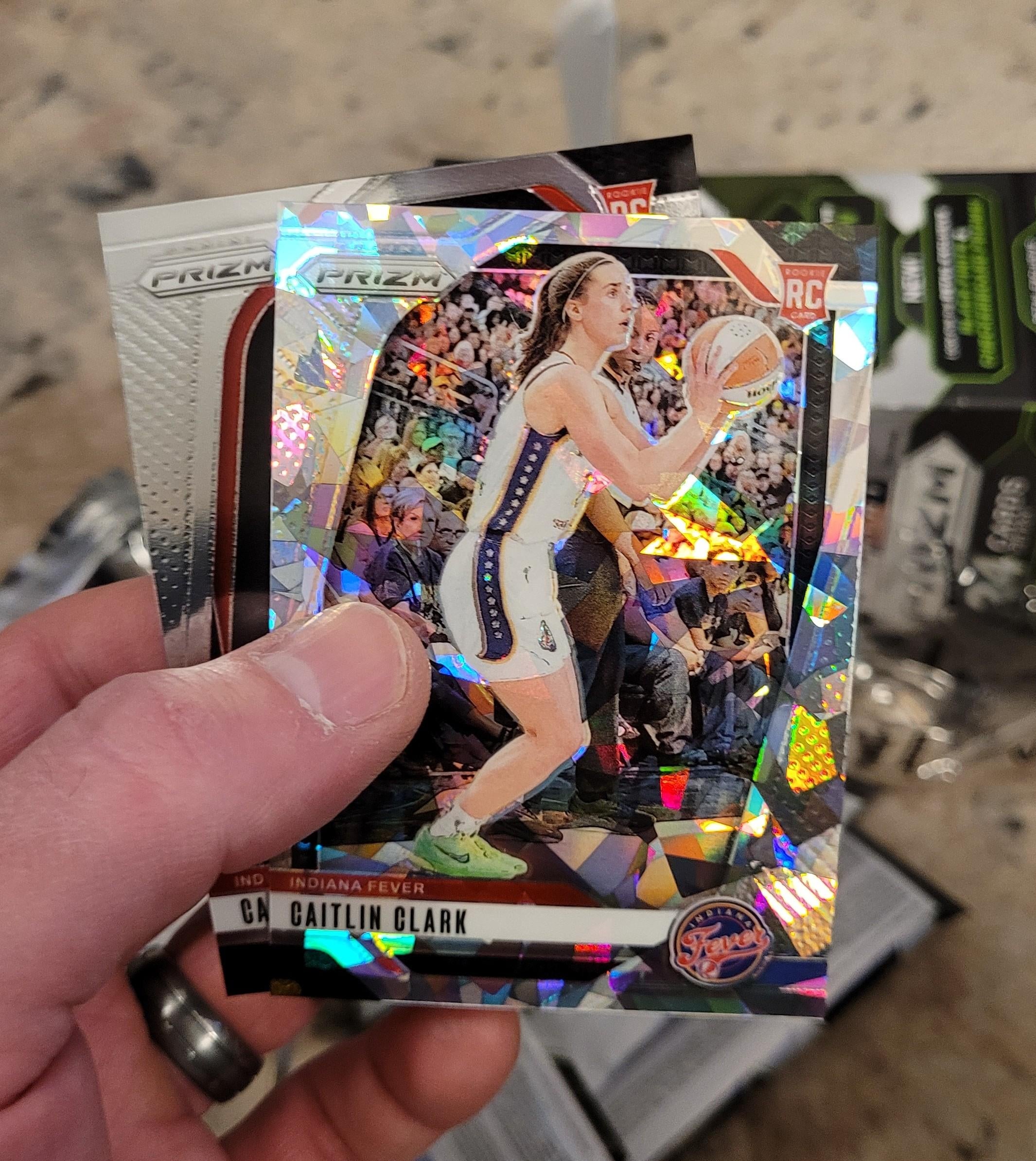 Tony Reid and his daughter, Izzy, pull a Caitlin Clark card from a pack of Panini Prizm WNBA Basketball. 