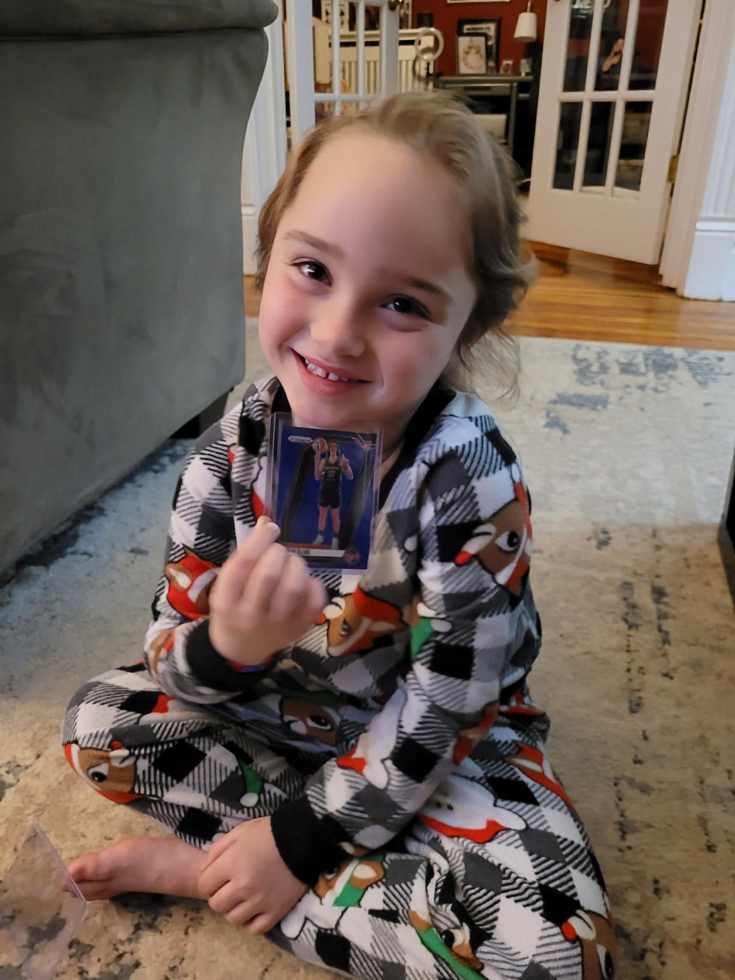 Izzy shows off a Caitlin Clark card from a pack of Panini Prizm WNBA Basketball. 