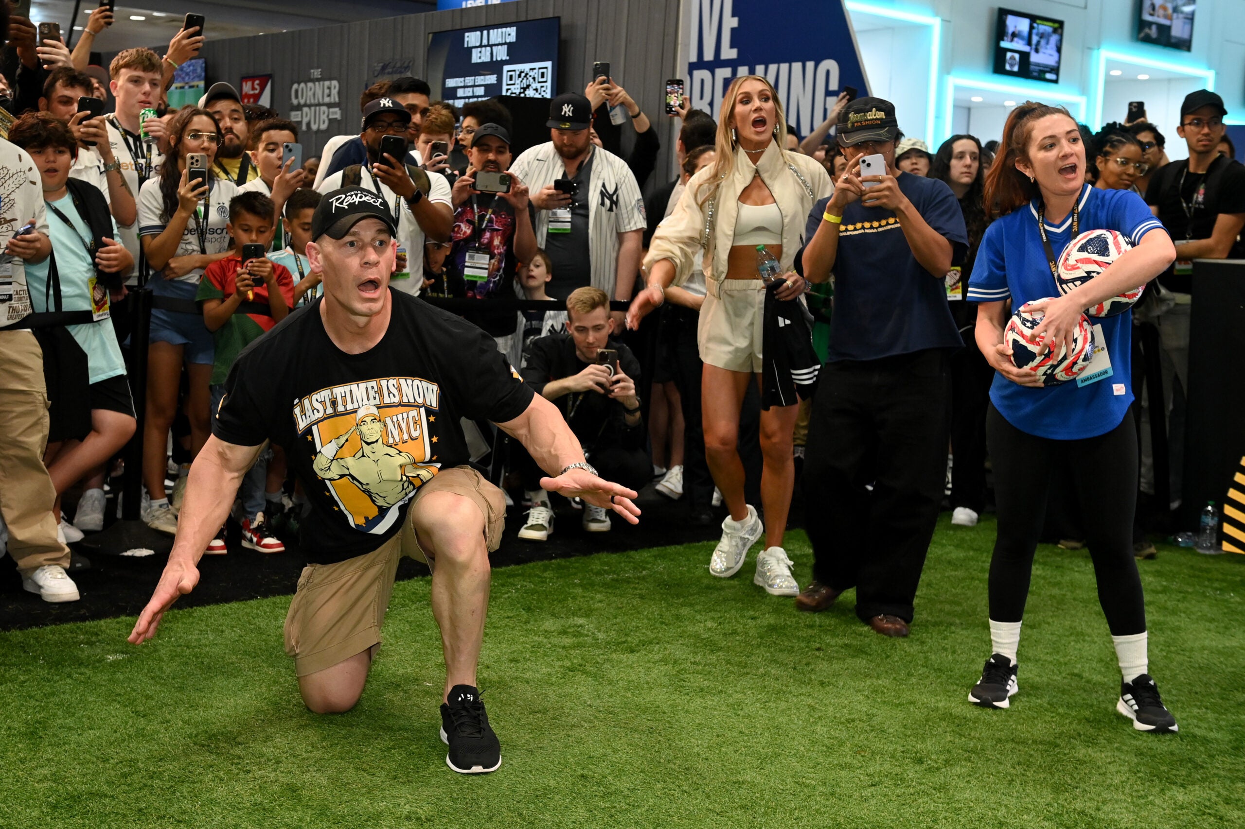 WWE stars John Cena and Charlotte Flair (background) entertain fans at Fanatics Fest NYC. 