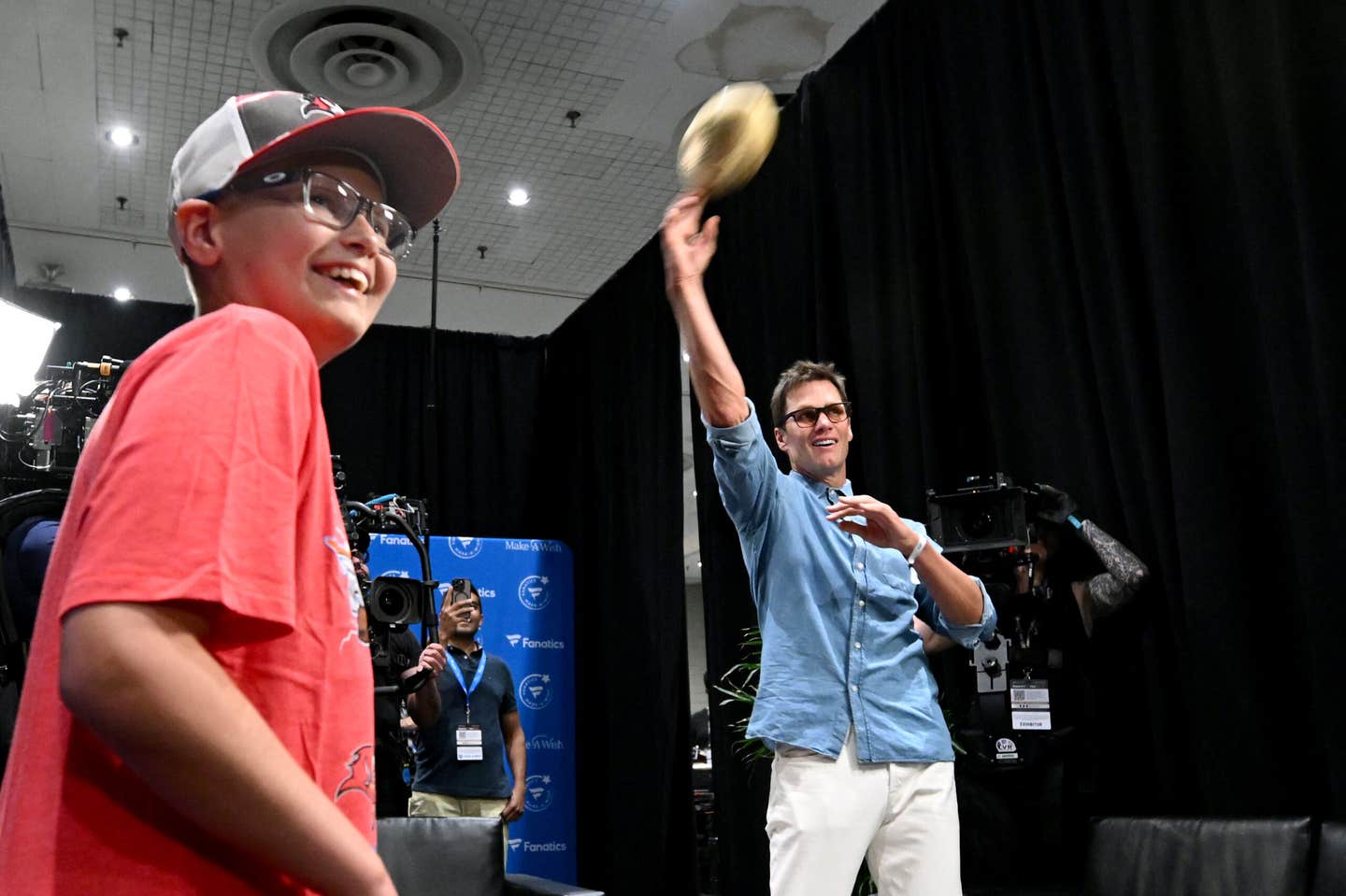 Tom Brady tosses a football with a young fan at Fanatics Fest NYC.