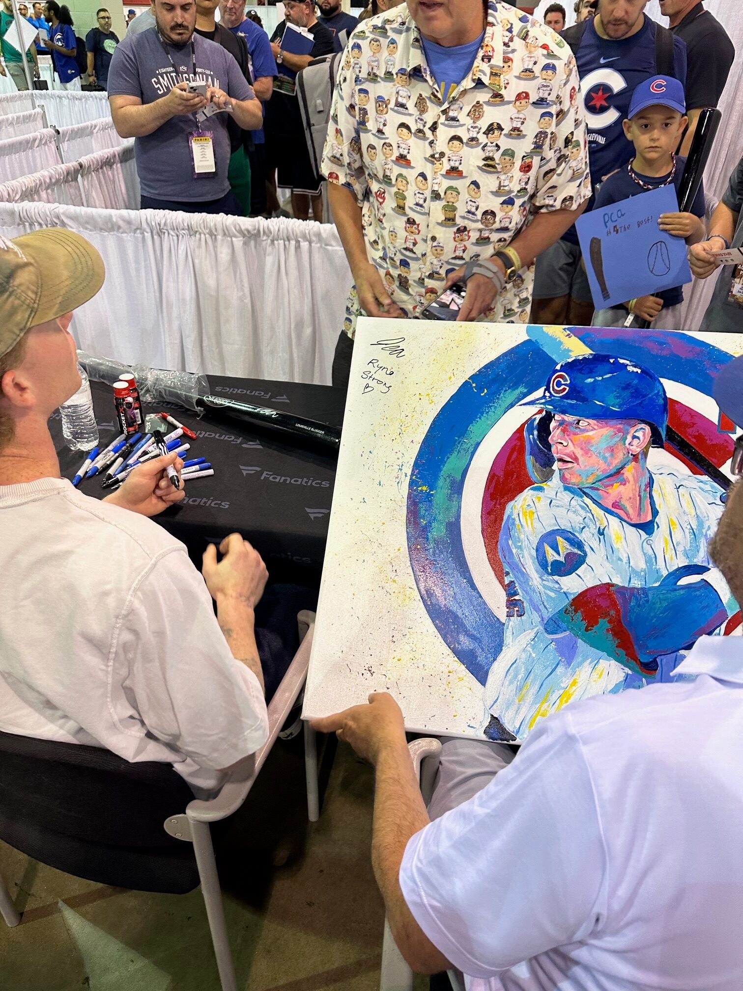 Pete Crow-Armstrong signs a special piece of artwork for charity. 