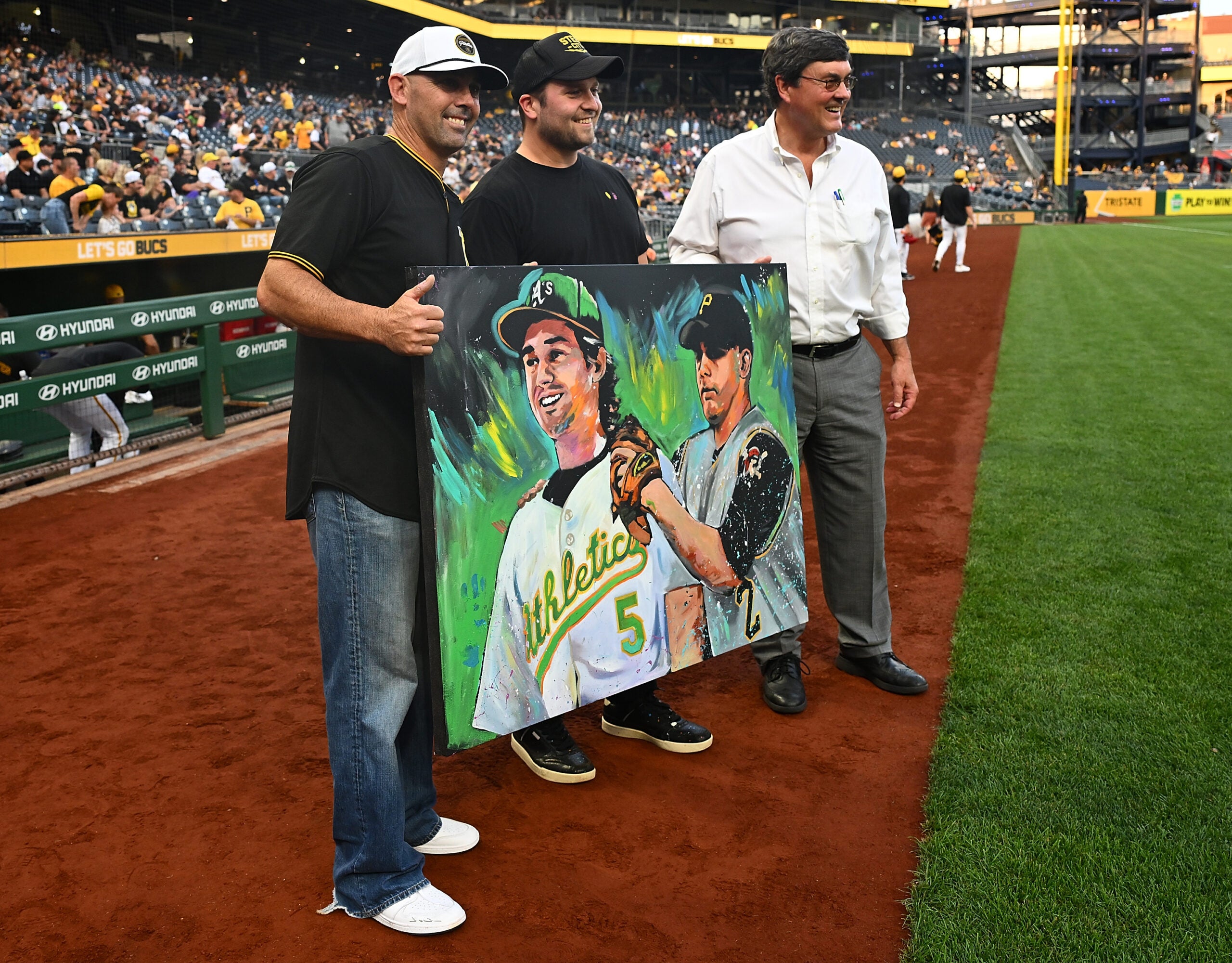 Pittsburgh Pirates owner Bob Nutting and artist Cody Sabol present a painting to former Pittsburgh Pirates player Jack Wilson of himself and his son Jacob before the game between the Pirates and Athletics at PNC Park on Sept. 19. 