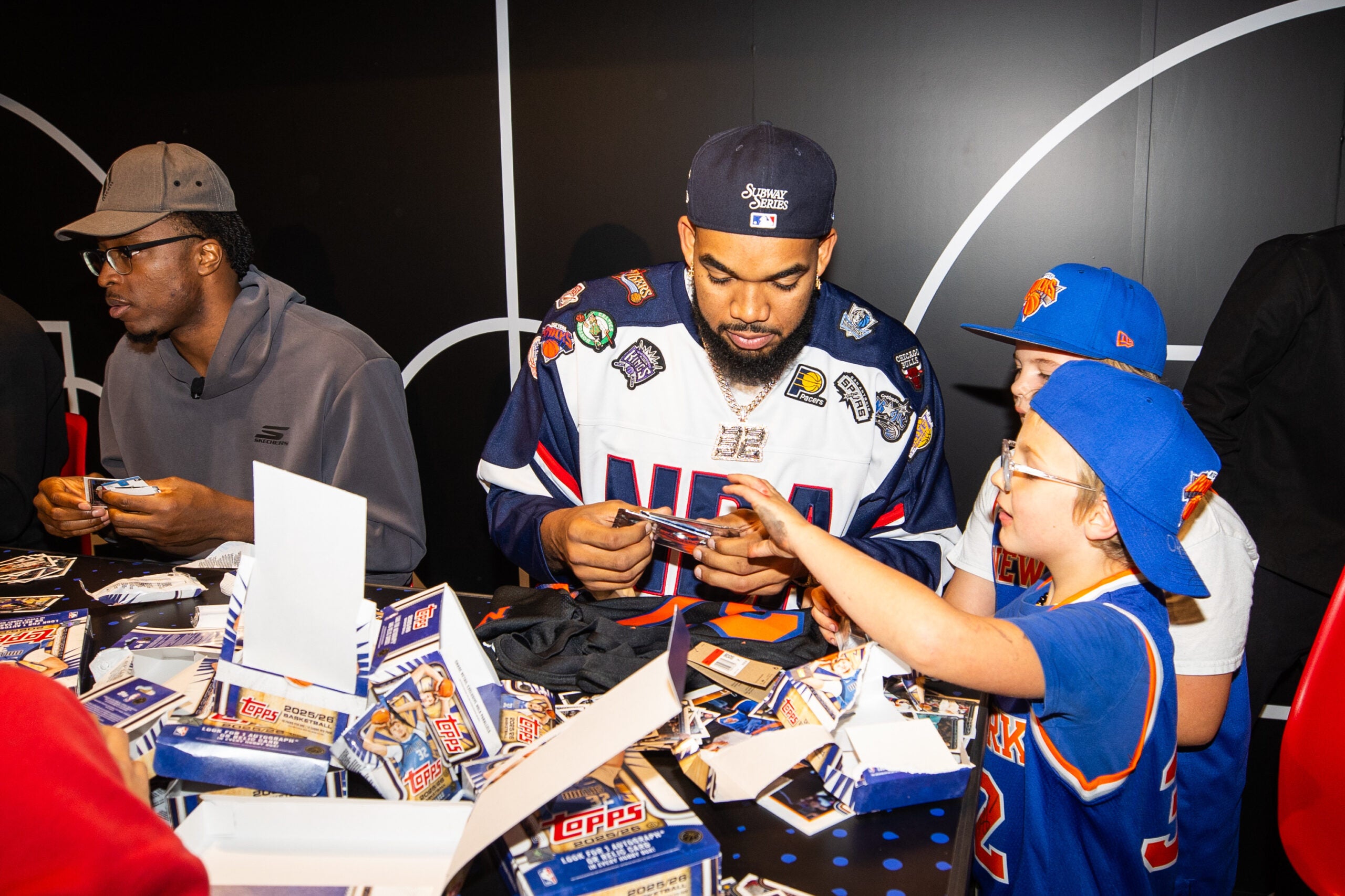 Knicks star Karl-Anthony Towns rips packs of cards with a young fan at the NBA Store in NYC. 