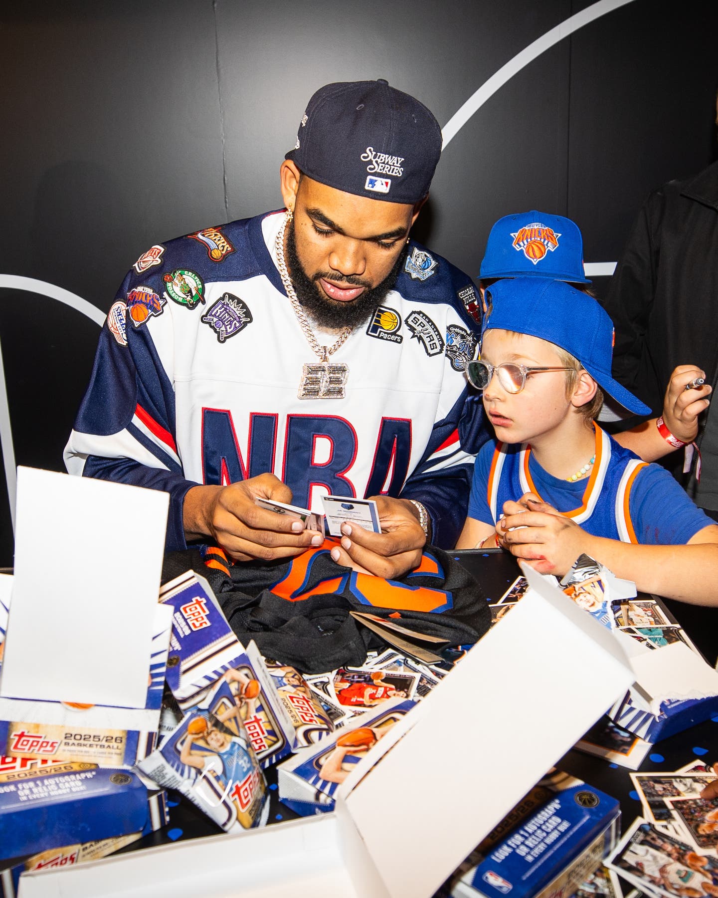 Karl-Anthony Towns rips packs of cards with a young fan at the Topps Basketball release party at the NBA Store in NYC.