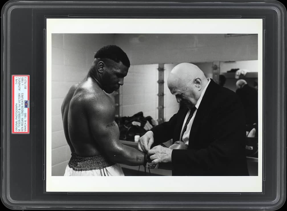 mar-6-1985-mike-tyson-pro-debut-type-i-original-photo-by-ken-regan---poignant-locker-room-shot-of-mentor-cus-damato-tenderly-lacing-his-18-year-old-proteges-glove-before-1st-win---psa_dna.png